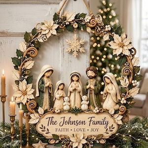 Può includere: Una ghirlanda decorativa circolare con stelle di Natale color crema, foglie verdi e una scena della natività centrale con cinque figure e due piccoli pupazzi di neve. Una targa in legno in basso riporta The Johnson Family FAITH • LOVE • JOY.