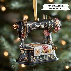 May include: Black sewing machine Christmas ornament with gold trim and floral patterns. The name "Anelia" is displayed on the ornament. The text on the image says "THIS ORNAMENT IS 2D FLAT, NOT 3D."