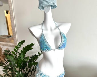 May include: A light blue crochet bikini set with a matching bucket hat. The bikini top and bottom are embellished with iridescent sequins. The set is displayed on a white mannequin.