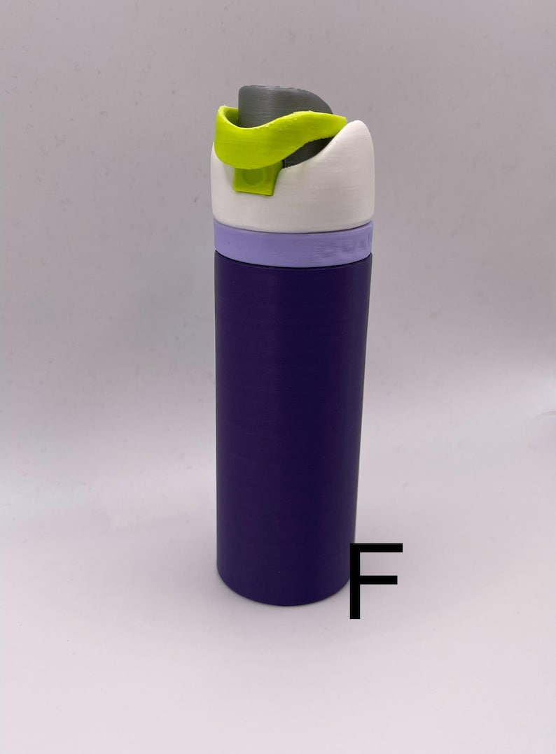 Peut inclure: Une bouteille d'eau violette avec un couvercle blanc et une boucle de transport verte. La bouteille a une bande violette clair autour du milieu.
