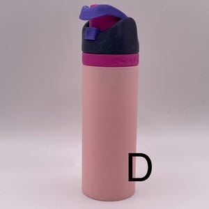 Peut inclure: Une bouteille d'eau rose avec un couvercle violet et noir. La bouteille a un couvercle &agrave; rabat et une boucle de transport.
