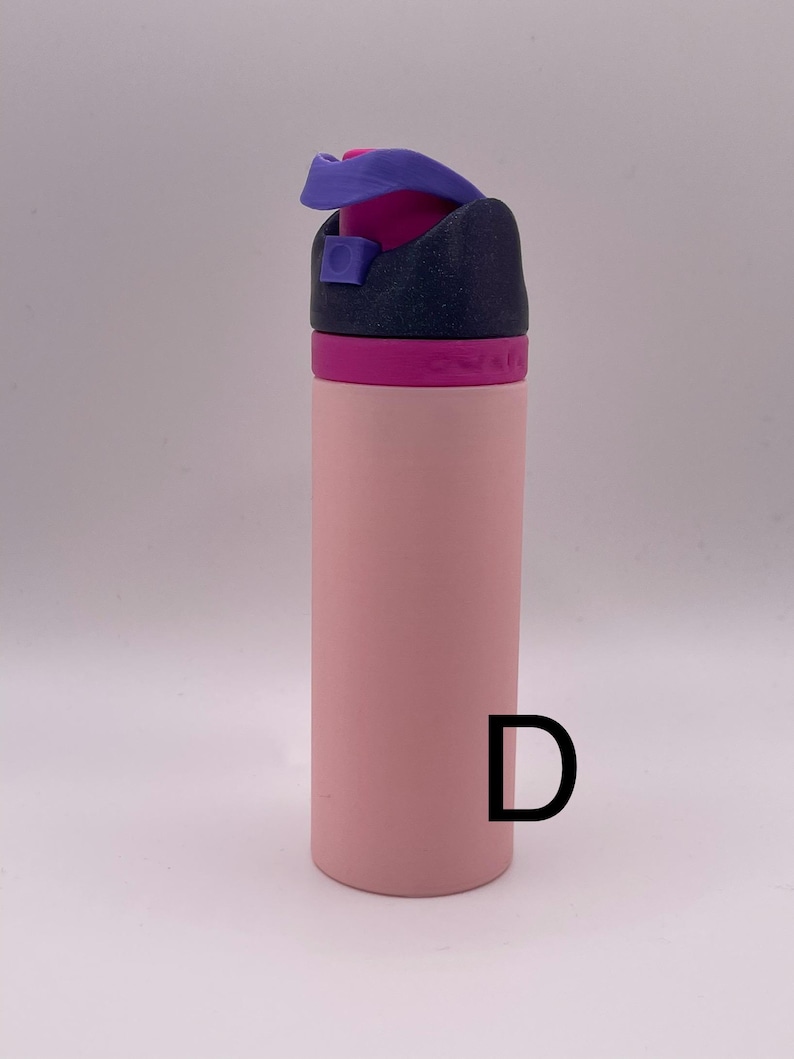 Peut inclure: Une bouteille d'eau rose avec un couvercle violet et noir. La bouteille a un couvercle &agrave; rabat et une boucle de transport.