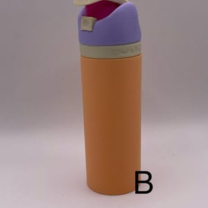 Peut inclure: Une bouteille d'eau r&eacute;utilisable avec un couvercle violet, blanc et rose. La bouteille est orange et a une finition mate.