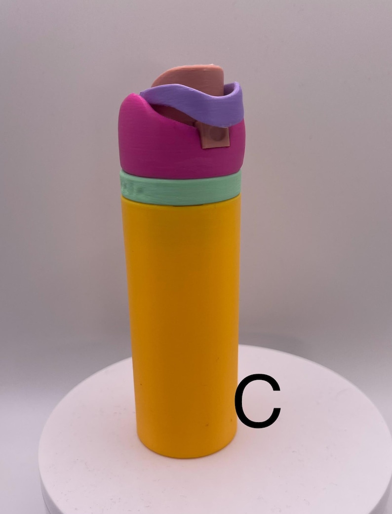 Peut inclure: Une bouteille d'eau r&eacute;utilisable jaune avec un couvercle rose, vert et violet. Le couvercle a un bouchon rabattable.