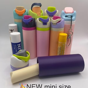 Peut inclure: Une collection de mini bouteilles d'eau color&eacute;es avec des couvercles et des breloques de diff&eacute;rentes couleurs. Les bouteilles sont dispos&eacute;es en demi-cercle avec un tube violet et un baume &agrave; l&egrave;vres au centre. Le texte "NEW mini size & SUMMER charms" est en bas de l'image.