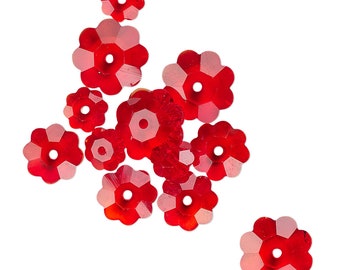 May include: A group of red crystal flower-shaped beads. The beads have a faceted design and a hole in the center for stringing.