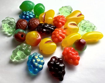 May include: A collection of colorful glass fruit charms, including red, orange, yellow, green, and blue. The charms are shaped like various fruits, such as strawberries, raspberries, lemons, limes, and grapes.