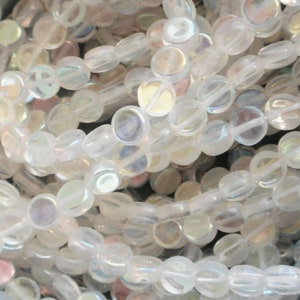 May include: A strand of iridescent white glass beads. The beads are round and flat, with a slightly oval shape. They have a subtle shimmer and are perfect for jewelry making.
