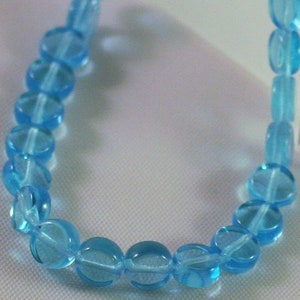 May include: A strand of light blue glass beads, each bead is round and slightly translucent.