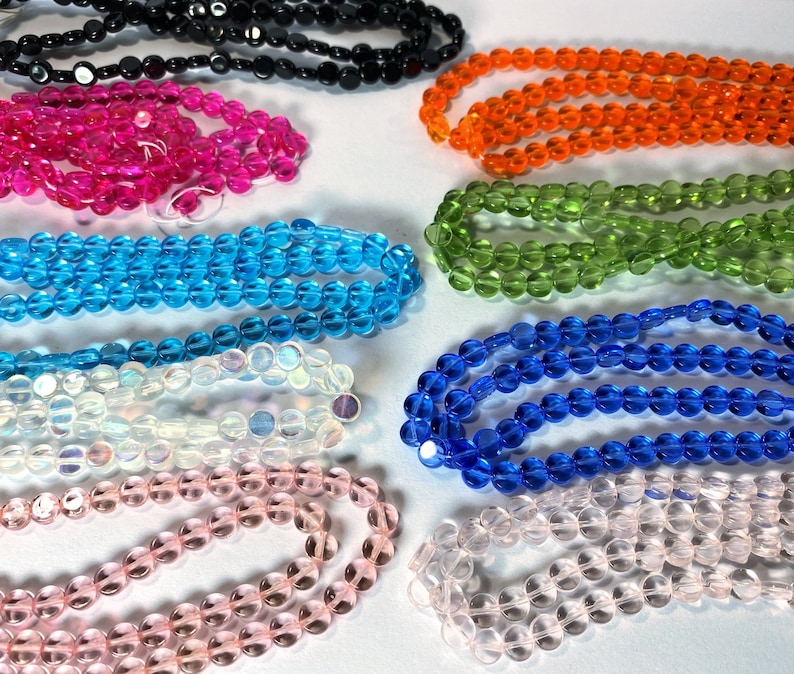 May include: Assortment of round glass beads in various colors, including pink, blue, green, orange, white, and clear. The beads are strung together in strands and are perfect for jewelry making or crafting.