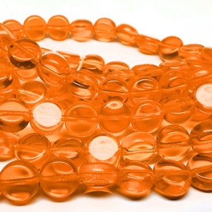 May include: A strand of round, translucent orange glass beads. The beads are approximately 10mm in diameter and have a slightly flattened shape.