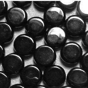May include: A close-up image of a group of black round glass tiles. The tiles are smooth and shiny, and they are arranged in a random pattern.