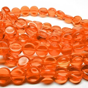 May include: A strand of round, orange glass beads. The beads are translucent and have a slightly faceted appearance.