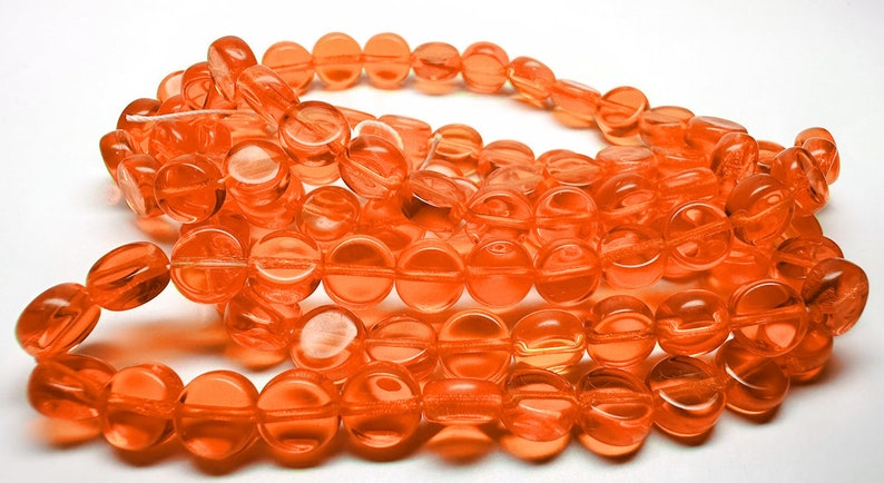 May include: A strand of round, orange glass beads. The beads are translucent and have a slightly faceted appearance.