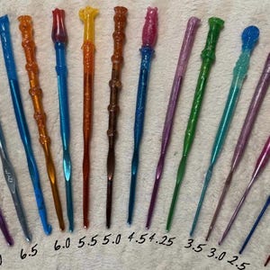 May include: A collection of colorful crochet hooks in various sizes, ranging from 2.0 to 7.0. The hooks are made of a translucent material and feature a variety of colors, including blue, red, purple, and green. The hooks are arranged on a white surface.