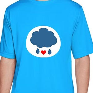 May include: A bright blue t-shirt with a white circular emblem. The emblem features a dark blue cloud, two blue raindrops, and a red heart. The shirt has short sleeves and is made of a smooth material.