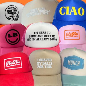 May include: A collection of trucker hats in various colors, including white, pink, red, and blue. Each hat features unique text or logos, such as "CIAO," "He He Hat Co.," and "I'm here to drink and get laid and I'm already drunk."