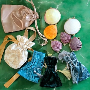 May include: Assortment of small fabric pouches in various colors and patterns, including gold, blue, and green. The pouches are tied with ribbons and have tassels.  There are also several decorative seashells in various colors and patterns.