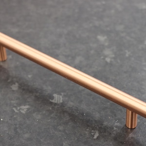 Può includere: Una maniglia per armadio in rame spazzolato con un design semplice e lineare. La maniglia è lunga circa 25 cm.