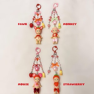 Puede incluir: Cuatro llaveros con peque&ntilde;as figuras, cada uno con un tema diferente de animal o fruta. Las figuras est&aacute;n unidas a cadenas decorativas con cuentas, lazos y abalorios. Las etiquetas de texto dicen "FAWN", "MONKEY", "MOUSE" y "STRAWBERRY".