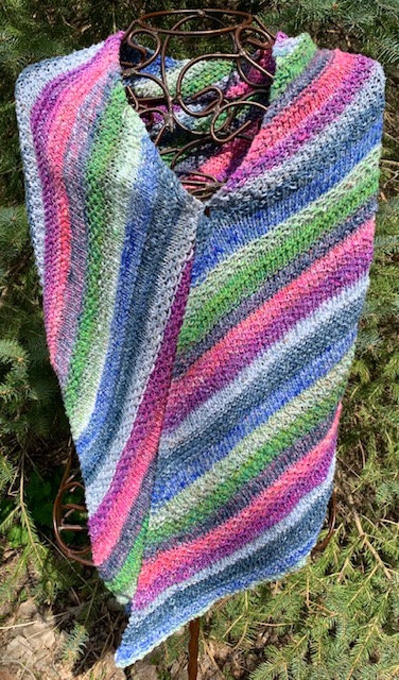 May include: A triangular knitted shawl with a diagonal striped pattern in shades of pink, blue, green, and grey.