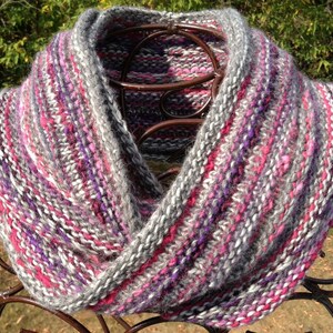 May include: A gray, pink, and purple knitted infinity scarf with a textured pattern.