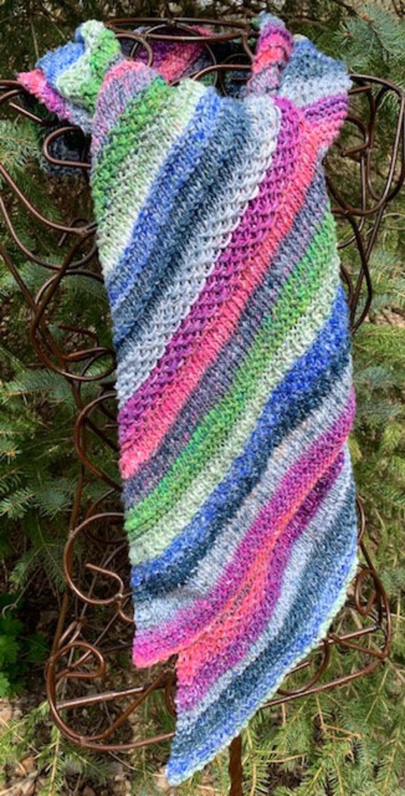 May include: A colourful striped knitted scarf with a diagonal pattern in shades of blue, green, pink, and white.