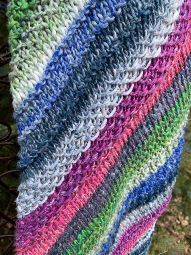 May include: A colourful knitted scarf with stripes of blue, green, pink and white.
