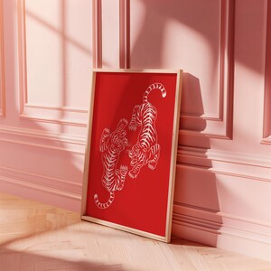 Peut inclure: Une impression encadr&eacute;e avec un fond rouge et deux tigres blancs se faisant face. Les tigres sont stylis&eacute;s et ont un design japonais traditionnel.