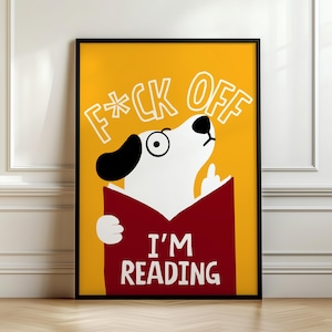 Könnte beinhalten: Gerahmtes Poster mit einem Comic-Hund, der ein Buch liest, vor einem gelben Hintergrund. Der Hund mit schwarz-weißen Markierungen zeigt den Mittelfinger. Der Text "F*CK OFF" und "I'M READING" ist in Weiß dargestellt.