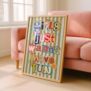 May include: A framed art print with the text "Girls Just Wanna Have Fun" in a colorful, collage-style design. The artwork features a light wood frame and a green and white striped background.