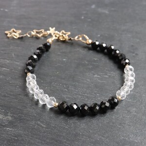 May include: A black and clear crystal bracelet with gold star charms. The bracelet is made with faceted beads and has a delicate chain.