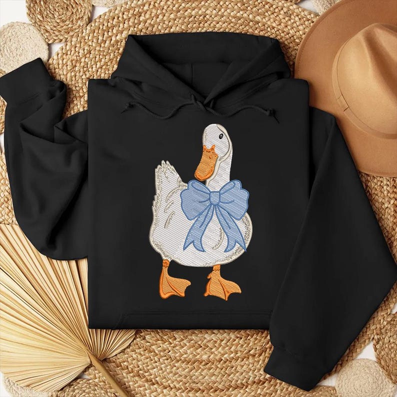 May include: Black hooded sweatshirt with a white duck wearing a blue bow tie embroidered on the front.