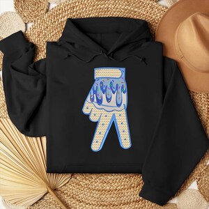 May include: Black hoodie with a blue and white ice cream cone hand design. The hand is making a peace sign and has sprinkles on it.