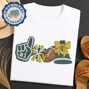May include: White t-shirt featuring embroidered sports-themed designs. The design includes a foam finger with the number one, a football, a cheerleader's megaphone, and a pom-pom. The design is in green, yellow, and brown.