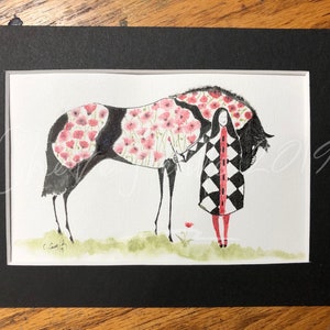 May include: A watercolor painting of a black horse with a pink floral pattern on its body. A woman in a black and white checkered coat stands next to the horse. The painting is framed in black.