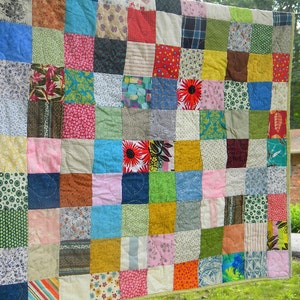 Puede incluir: Un edred&oacute;n hecho a mano con un dise&ntilde;o de patchwork. El edred&oacute;n est&aacute; compuesto por numerosos cuadrados de tela en varios colores y patrones, incluyendo dise&ntilde;os florales, a rayas y lisos. El edred&oacute;n tiene un borde verde.