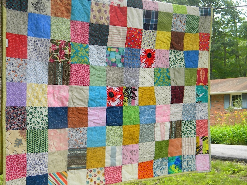 Puede incluir: Un edred&oacute;n hecho a mano con un dise&ntilde;o de patchwork. El edred&oacute;n est&aacute; compuesto por numerosos cuadrados de tela en varios colores y patrones, incluyendo dise&ntilde;os florales, a rayas y lisos. El edred&oacute;n tiene un borde verde.