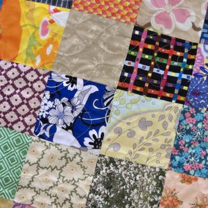May include: A patchwork quilt with a variety of colorful floral and geometric patterns. The quilt is made up of many different squares, each with a unique design.