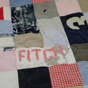 Pode incluir: Uma colcha de retalhos feita de diferentes tecidos, incluindo tecido listrado azul e branco, tecido xadrez vermelho e branco e um pedaço de tecido com as palavras "FITCH NEW YORK" bordadas.