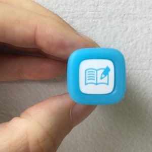 May include: A blue square-shaped stamp with a white icon of an open book and a pencil.