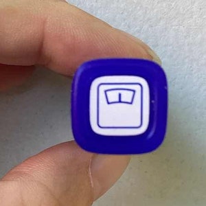 May include: A close-up of a purple pen with a white scale symbol on the cap.