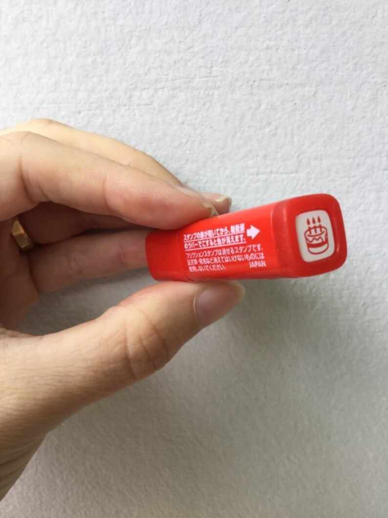 May include: Red plastic stamp with a cake design and the text "スタンプのがあいてから、●バーでとするときが来ます。フリクションスタンプは消せるスタンプです。・名など消えてはいけないものには使用しないでください。JAPAN" on the side.