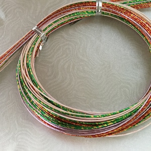 May include: A spool of metallic trim with red, green, and gold accents. The trim is wound in a circle and is ready to be used for crafting projects.