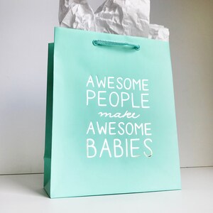 May include: A light blue gift bag with white rope handles. The bag has white text that reads "Awesome People make Awesome Babies."
