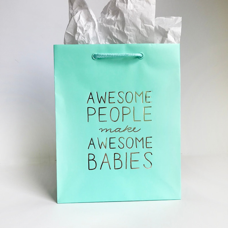 May include: A light blue gift bag with a white rope handle. The bag has gold lettering that reads "Awesome People make Awesome Babies."