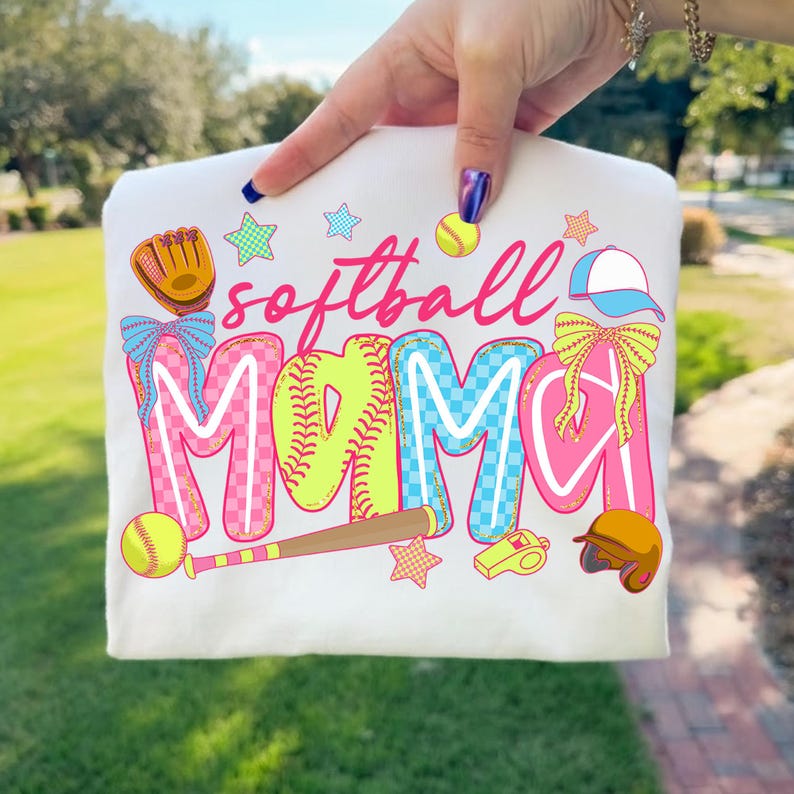 May include: A white t-shirt with the words "softball mama" in pink, yellow, and blue. The design includes softball-themed graphics like a glove, ball, bat, helmet, and stars.