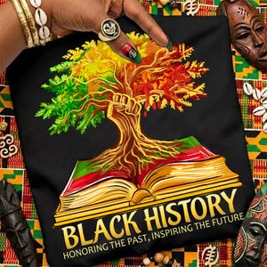 May include: Black t-shirt with a vibrant tree design, a fist, and an open book. The text reads "BLACK HISTORY" and "HONORING THE PAST, INSPIRING THE FUTURE" in gold lettering. The tree's leaves are green, yellow, and red.