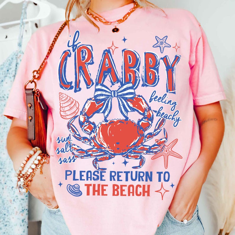 May include: Pink t-shirt with a crab graphic in red and blue, and the text "If Crabby, Please Return to the Beach." The design includes a seashell, starfish, and the words "sun, salt, sass, feeling beachy."