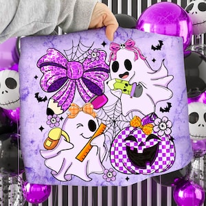 May include: A purple and white Halloween-themed pillow featuring cartoon ghosts, a bow, a pumpkin, and bats. The design includes a large bow, spiderwebs, and a checkered pumpkin. The ghosts are holding pencils and rulers.